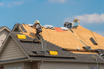 Roofers carrying a heavy stack of shingles