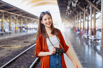 Young Asian woman traveler wearing orange shirt with taking picture using a camera at temple. summer tourism concept.