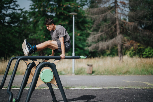 Man working out his abs by exercising on parallel bars in a park setting outdoors