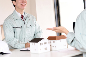 建設模型を使い会議をする作業服を着た男女