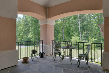 Stone Tile Terrace With Wrought Iron Furniture Set Under Covered Porch View