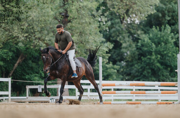 Man riding a horse in an outdoor arena, engaging in equestrian practice. The background features...