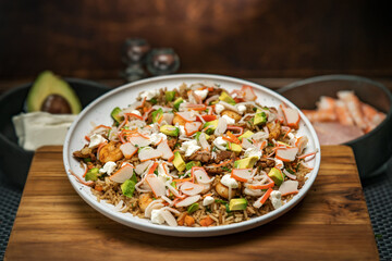 ensalada de surimi, aguacate, queso crema , verduras en una cama de arroz frito