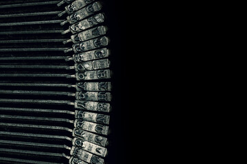 Macro photograph of typewriter hammers on a black background with room for copy.