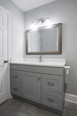 Modern Bathroom Vanity With Gray Cabinets Under A Well-Lit Wall-Mounted Mirror