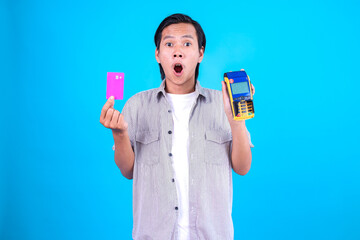 Young Man Holding EDC Machine And Bank Card With Shocked Expression