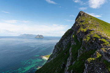 Turquoise blue atlantic ocean, lofoten mountains, and seaside cliffs seen in a vibrant landscape...