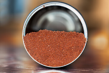 Opened can of ground coffee with lying on metal kitchen table with blurred background