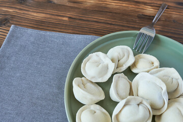 Frozen dumplings. Dumplings in green plate on wooden background. 