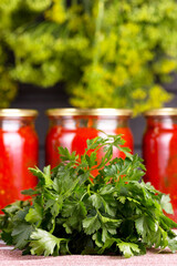 Tomato sauce in a glass jar, tomatoes and herbs. Harvesting and canning.