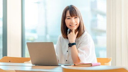 Obraz premium パソコンで仕事をする笑顔の日本人ビジネスウーマン