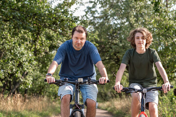 Obraz premium People riding on bicycles outdoor in nature, father and son cycling together in park