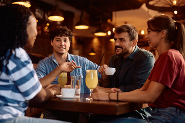 Young happy people communicating while gathering in café.