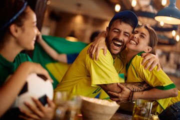 Happy couple of fans embracing while celebrating victory of their favorite sports team.
