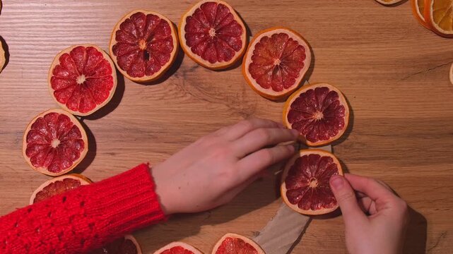 Step 1 Woman using hot glue Handmade Christmas wreath from dried orange grapefruit slices. Festive holiday preparation craft master class of creative making decor. Hands-on activities sustainable