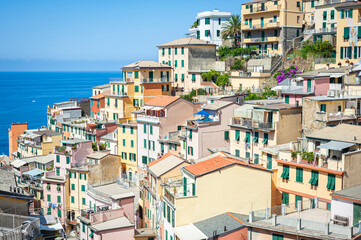Classic light colored italian houses on a cliff in the village of Riomaggiore, one of the villages of Cinque Terre, Italy