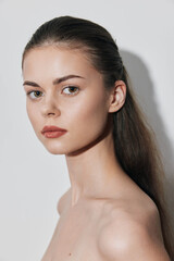 Naklejka premium Portrait of a gorgeous young woman with long brown hair posing in front of a white wall
