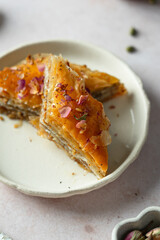 Piece of baklava with rose petals on a plate