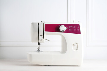 Modern sewing machine on white wooden table indoors