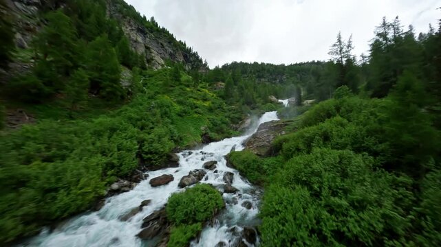 Cascading Rutor Waterfall amidst lush green forest in Aosta Valley, Italy, aerial view