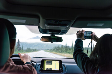 Couple driving in Denali National Park and Preserve in the rain. Passenger taking photos using a smartphone. Alaska. USA.