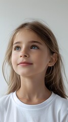 Naklejka premium portrait of a cute blonde girl in a white t-shirt looking up