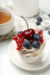 Tasty cupcake with different berries and tea on white marble table, closeup