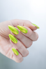 Female hand with long nails and a bright yellow green nail polish