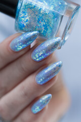 Female hand with long nails and bright light blue and silver manicure	
