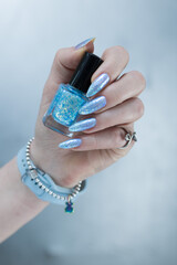 Female hand with long nails and bright light blue and silver manicure	