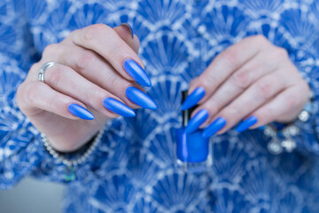 Fototapeta premium Woman's beautiful hand with long nails and bright blue manicure