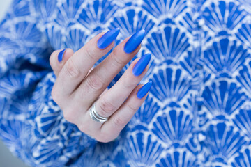 Woman's beautiful hand with long nails and bright blue manicure