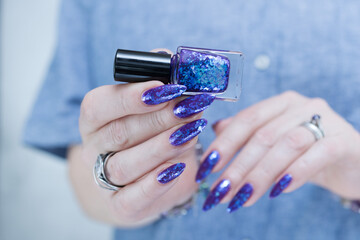 Female hand with long nails and a blue and purple color nail polish