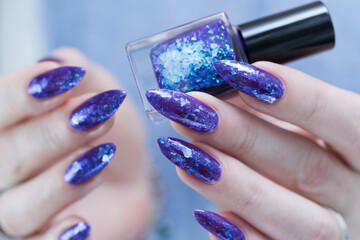 Female hand with long nails and a blue and purple color nail polish