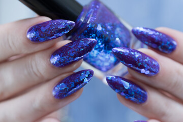 Female hand with long nails and a blue and purple color nail polish