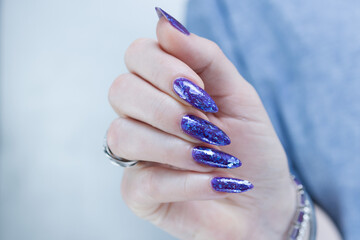 Female hand with long nails and a blue and purple color nail polish