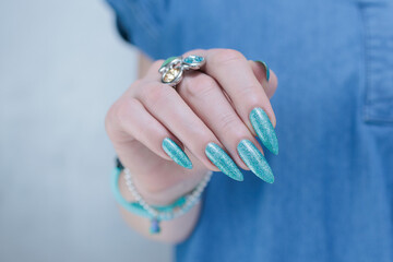 Female hand with long nails and light turquoise manicure, blue and green color