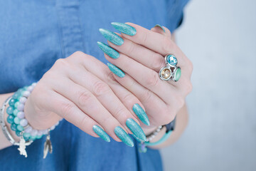 Female hand with long nails and light turquoise manicure, blue and green color