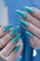 Female hand with long nails and light turquoise manicure, blue and green color