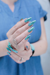 Female hand with long nails and light green and blue turquoise manicure 