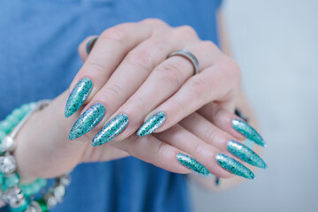 Female hand with long nails and light green and blue turquoise manicure 