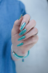 Female hand with long nails and light turquoise manicure, blue and green color