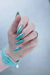 Female hand with long nails and light green and blue turquoise manicure 
