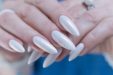 Woman's hands with long nails and a light white color nail polish