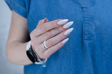 Woman's hands with long nails and a light white color nail polish
