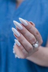 Woman's hands with long nails and a light white color nail polish