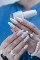 Woman's hands with long nails and a light white color nail polish