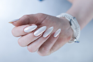 Woman's hands with long nails and a light white color nail polish