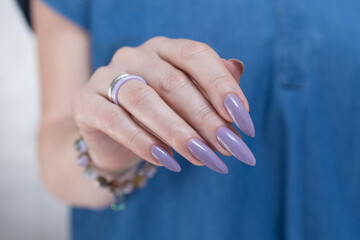 Female hand with long nails and a lilac nude nail polish