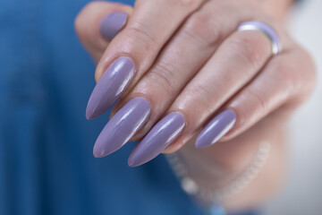 Female hand with long nails and a lilac nude nail polish